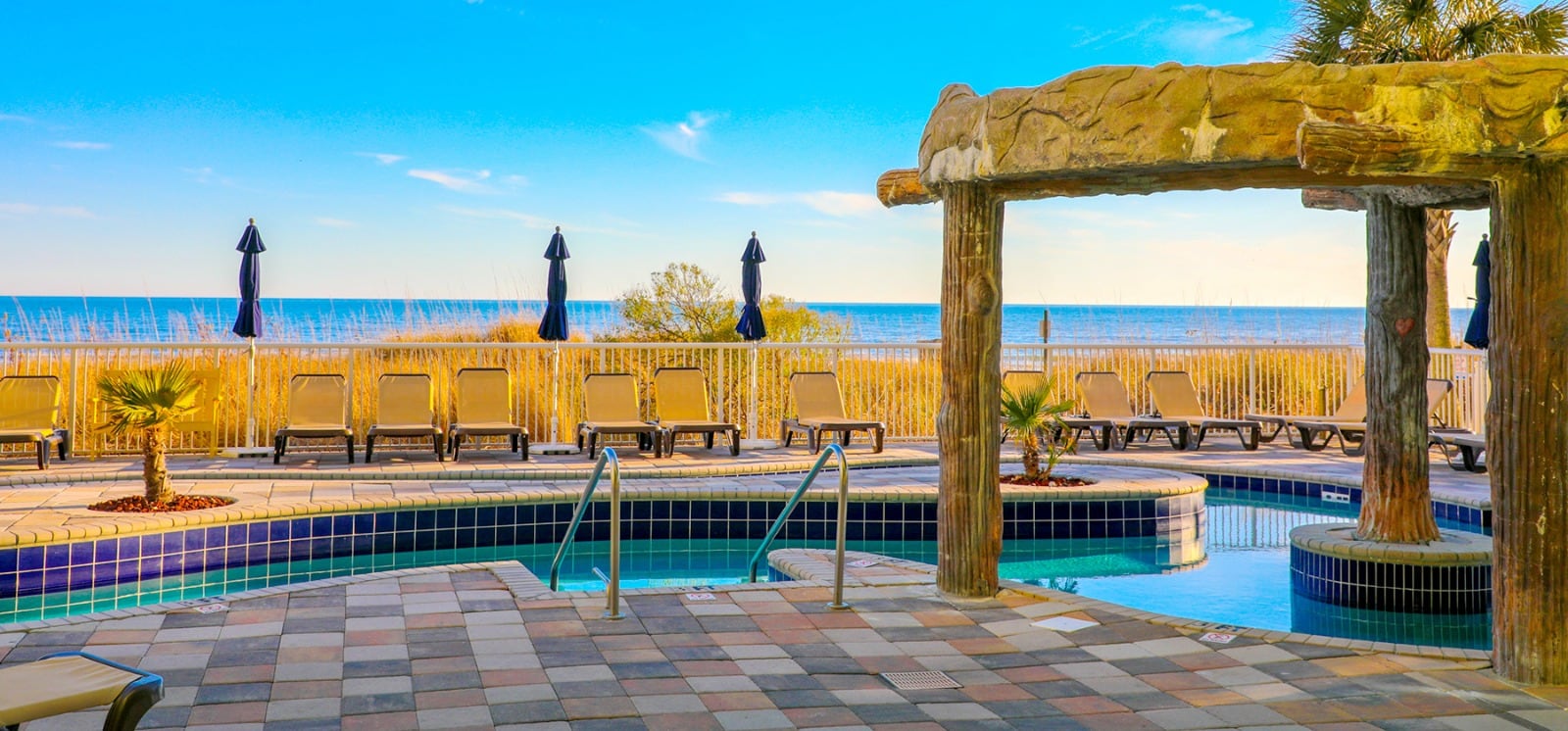 The outdoor pool of Myrtle Beach Seaside Resort featuring beach chairs in view